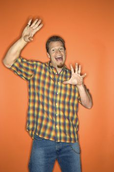 Portrait of surprised-looking adult Caucasian man on orange background.