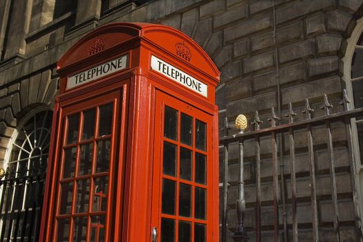Classic bright red British telephone box set against ornate building