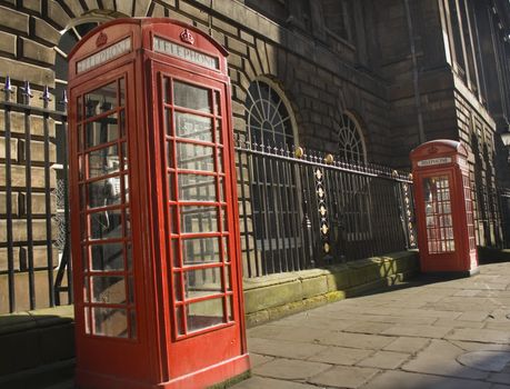 Pair of classic bright red British telephone boxs set against ornate building