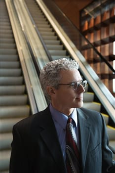 Close up of prime adult Caucasian man in suit on escalator.