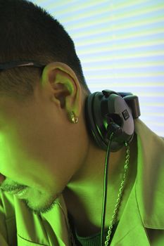 Close-up of Asian young adult male DJ's ear and profile with headphones.