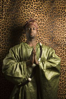 Portrait of African- American mid-adult man in prayer wearing traditional African clothing.