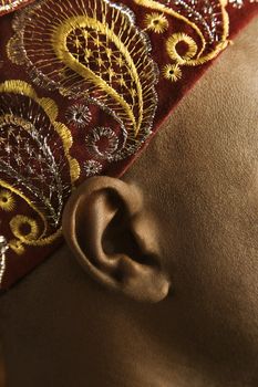 Close-up side view of African-American mid-adult man wearing traditional African hat.