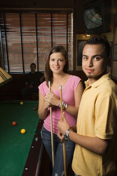 Portrait of young man and woman playing billiards.