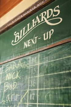 Chalkboard queue for people waiting to play billiards in nightclub.