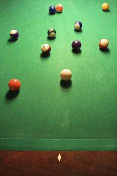 Green billiards table with pool balls spread out.