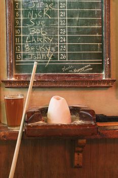 Chalkboard queue for people waiting to play billiards in nightclub with chalk and pool stick.