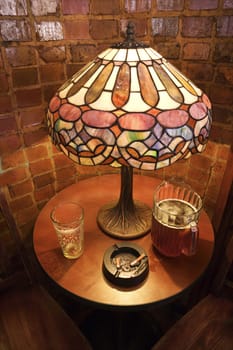 High angle still life of table with beer glass, pitcher, and cigarette ashtray in nightclub.