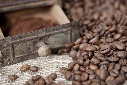 Antique coffee grinder filled with coffee beans and ground coffee - selective focus