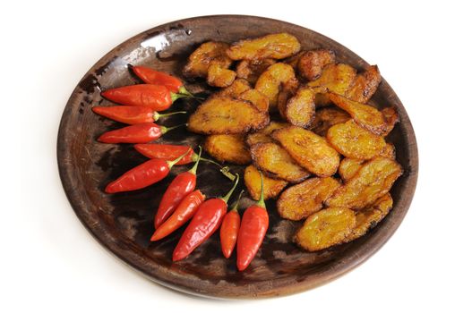 Typical cuban food on wooden dish isolated - fried babana and chili peppers