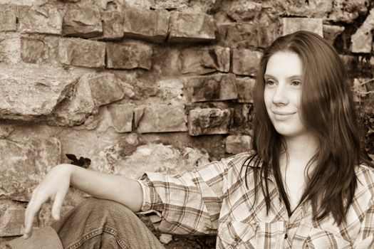 Girl sitting near old wall 
