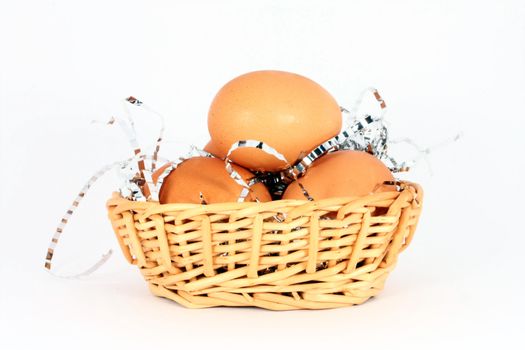 Chicken egg in a basket with decorations, isolated
