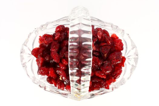 Glass basket full of dried cranberries, isolated on white