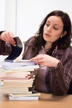 young student holding her head over books