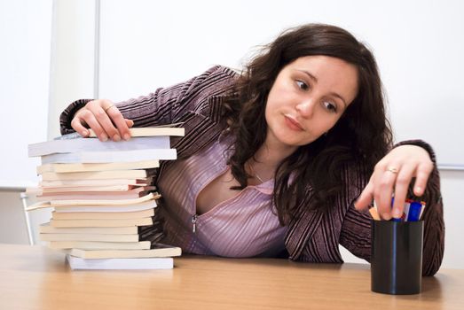 young student holding her head over books