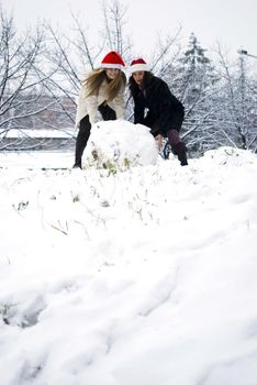 two girls making big snowball