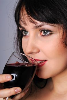 a charming young lady holding a glass of red wine