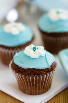 Cupcakes decorated with blue frosting and sugar flowers