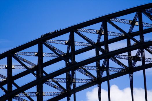 Sydney Harbour Bridge climbers silhouetted against a blue sky
