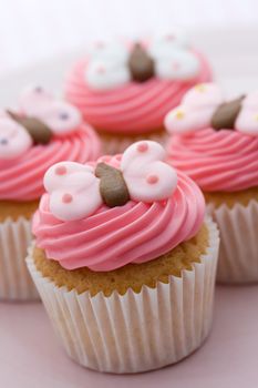 Cupcakes decorated with pink frosting and sugar butterflies
