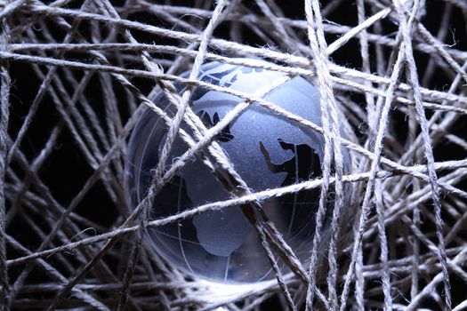 Glass globe inside gray crossing rope on dark background