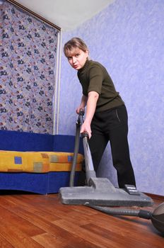 beautiful young housewife with vacuum cleaner in a room 