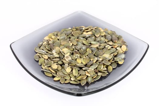 Pumpkin seed on glass plate, isolated on white