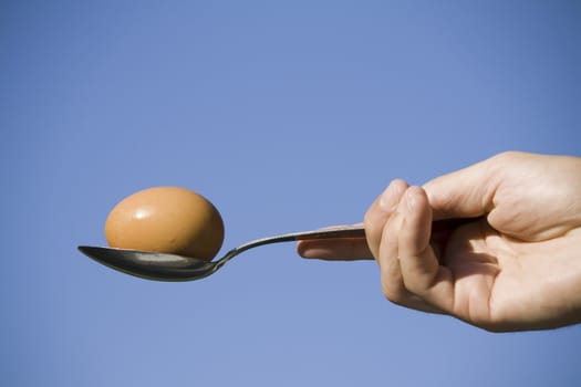 hand holding an egg in spoon