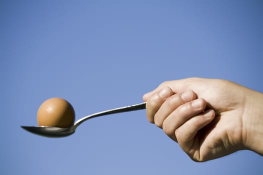 hand holding an egg in spoon