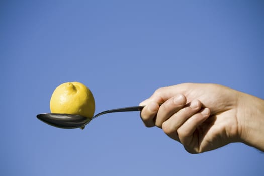 hand holding a lemon in spoon