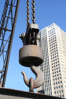 Big lifting hook with backdrop of highrise office building
