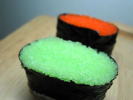 2 slide of Tobiko Gunkan sushi, one original, one with wasabi taste.