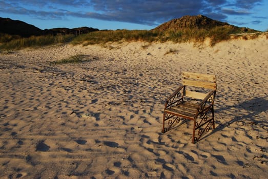 a chair standing on a beach facing the sea