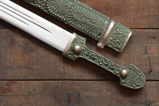 Closeup of antique caucasian dagger and scabbard on wooden background