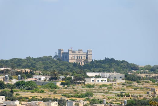 View on Verdala Palace as seen from Dingle Cliffs at 2km distance through the heat haze of Southern Maltese countryside.
