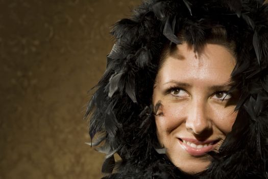 Pretty Hispanic Woman Wearing a Feather Boa in front of Gold Wallpaper