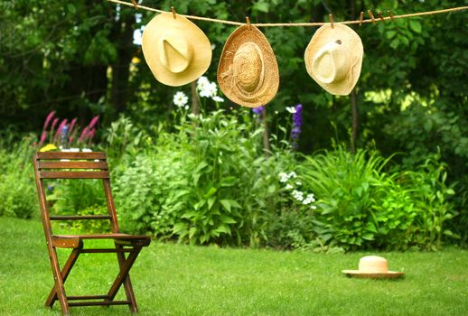 Straw hats on an old clothesline in a summer garden