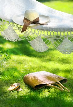 Straw hat with brown ribbon laying on summer hammock