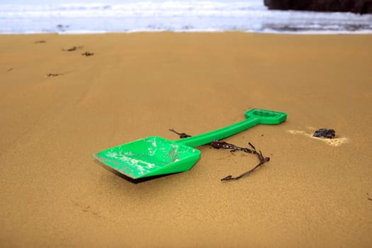 green plastic spade abandoned lying on a beach in ireland
