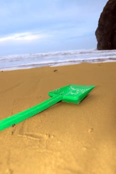 green plastic spade abandoned lying on a beach in ireland
