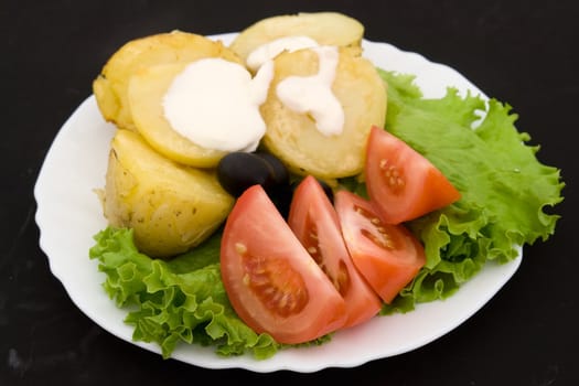 Potatoes, tomatoes and salad on a white plate