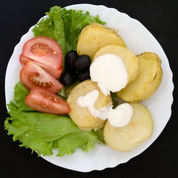 Potatoes, tomatoes and salad on a white plate