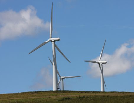 Wind Farm Power Turbines Carno Wales UK against a blue sky with white clouds,rural sheep farming area