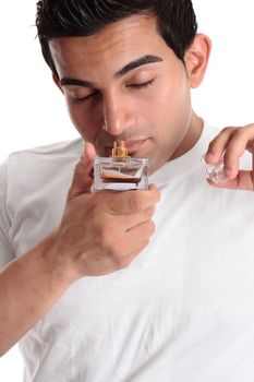 A man holds a bottle of perfume to his nose to smell the scent.
