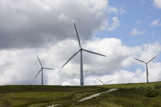 Wind Farm Power Turbines Carno Wales UK against a blue sky with black clouds,rural sheep farming area