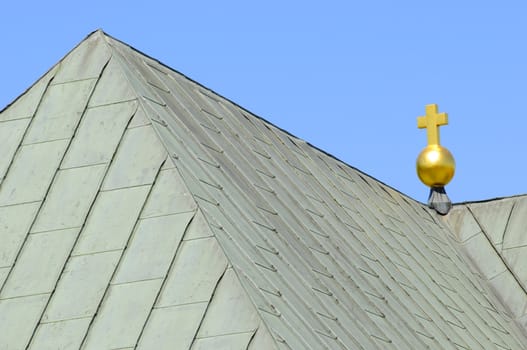 golden cross on top of sheet metal church roof