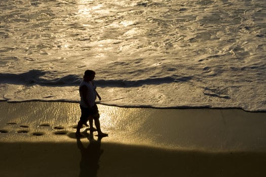 Couple walking hand in hand on the beach at sunset