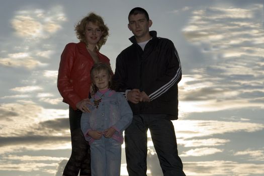 Young family against a sunset and the sky with clouds