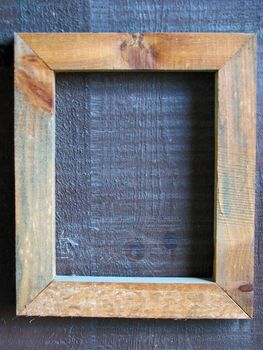 An empty wooden frame on a wooden wall.

