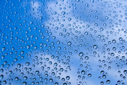 Water drops against blue sky with clouds.